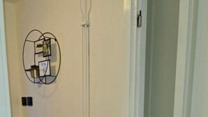 A hallway with a radiator, a potted plant, and a wall-mounted light fixture. - Independent apartment with kitchen (Norrbottens län)