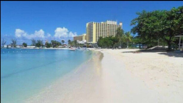 A beach with a hotel in the background.