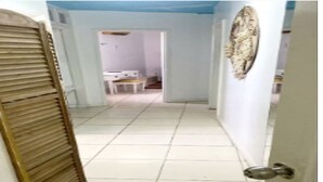 A hallway with a tiled floor, a closed wooden door, and a wall-mounted decorative plate.