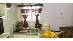 A kitchen with a sink, a microwave, and a fruit basket.