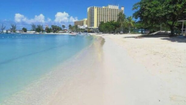 Ein Strand mit einem Hotel im Hintergrund.