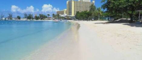 A beach with a hotel in the background.