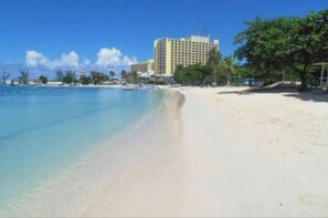 A beach with a hotel in the background. - Cozy 1 of 5 Apartment in the Heart of Ocho Rios (Ocho Rios)