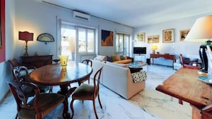 Un amplio salón con una mesa redonda de madera, un sofá y un televisor.