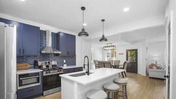 A modern kitchen with a central island, stainless steel appliances, and a dining area with a chandelier. - Columbus: Victorian Villa (Columbus)