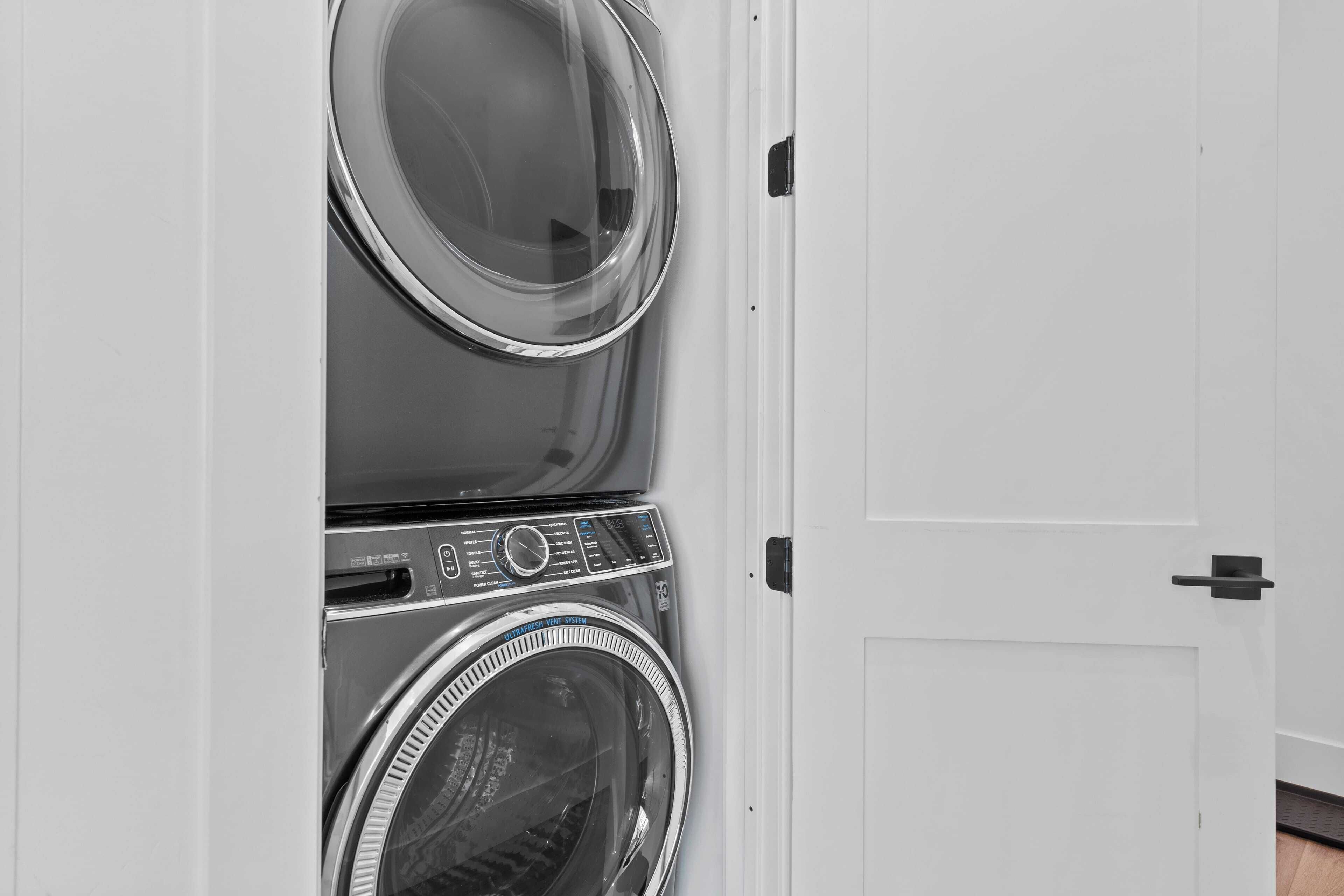 A front view of a stacked washer and dryer unit with a door to the right.