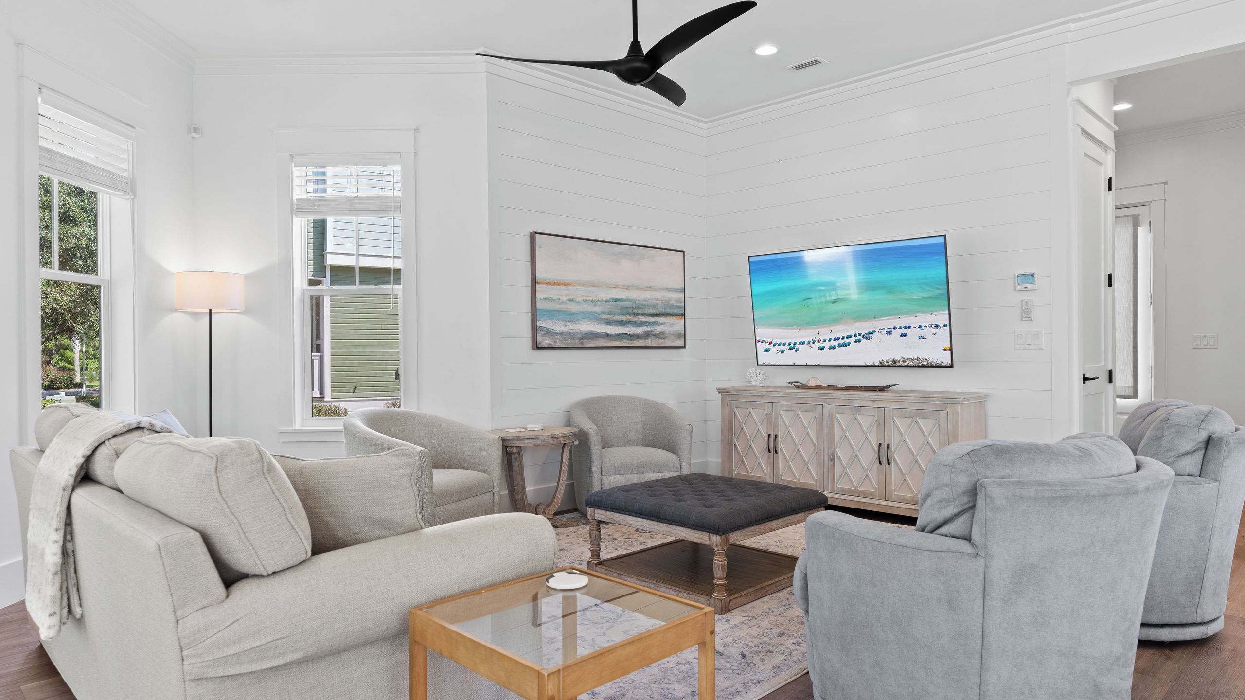 A living room with a sofa, armchairs, a coffee table, a TV, and a ceiling fan.