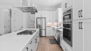 A modern kitchen with white cabinetry, stainless steel appliances, and a central island. - Lagniappe at Blue Mountain by Avantstay 4BR Coastal Home + Walk to the Beach Community Pool + Gym (Santa Rosa Beach)