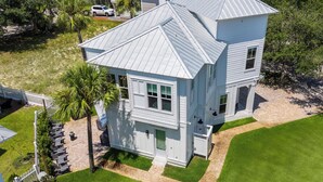 A two-story building with a gabled roof, a covered porch, and a small front yard with a palm tree. - Lagniappe at Blue Mountain by Avantstay 4BR Coastal Home + Walk to the Beach Community Pool + Gym (Santa Rosa Beach)