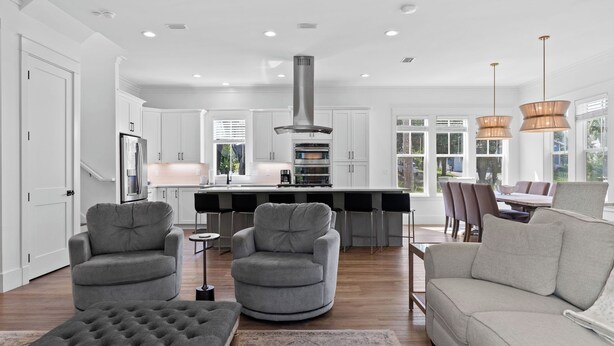 A modern kitchen with white cabinetry, a central island, and a stainless steel range hood. - Lagniappe at Blue Mountain by Avantstay 4BR Coastal Home + Walk to the Beach Community Pool + Gym (Santa Rosa Beach)