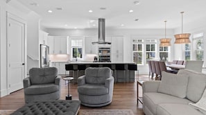A modern kitchen with white cabinetry, a central island, and a stainless steel range hood. - Lagniappe at Blue Mountain by Avantstay 4BR Coastal Home + Walk to the Beach Community Pool + Gym (Santa Rosa Beach)