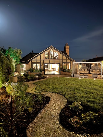 A house with a large front porch, a well-maintained lawn, and a pathway leading to the entrance.. Balancyoga Guesthouse