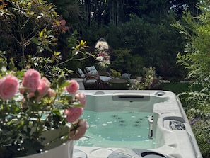 A hot tub surrounded by lush greenery and a garden with a gazebo. - Balancyoga Guesthouse (West Kingsdown)