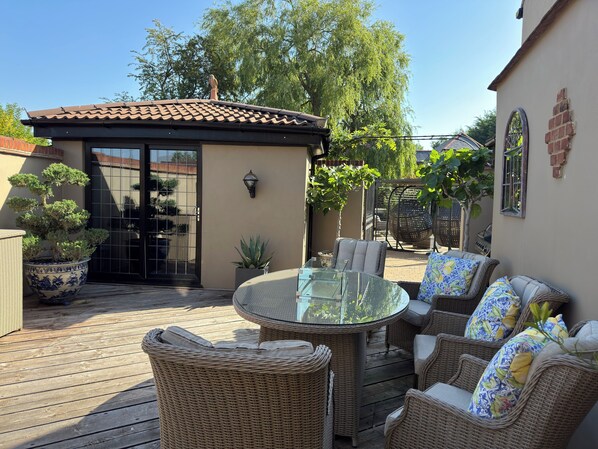 A patio with wicker furniture, a glass table, and potted plants. - Balancyoga Guesthouse (West Kingsdown)