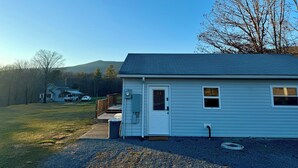 A single-story house with a front porch, a small garage, and a clear view of a mountain in the background. - Charming 1-bedroom cottage in Covington with AC (Covington)