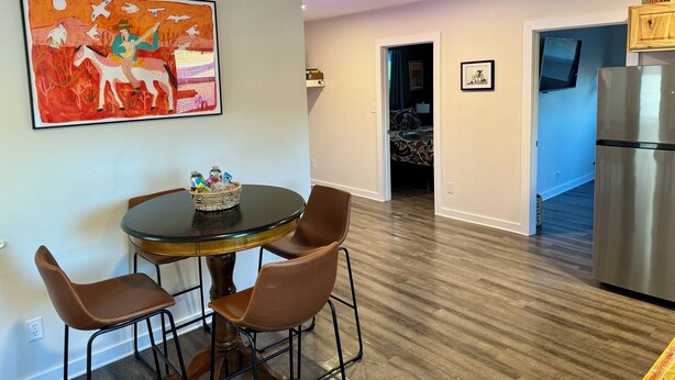 A dining area with a round table, two chairs, a ceiling fan, and a wall-mounted painting. - Charming 1-bedroom cottage in Covington with AC (Covington)