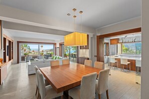 A spacious dining area with a wooden table and chairs, a large pendant light, and a view of the outdoors.
