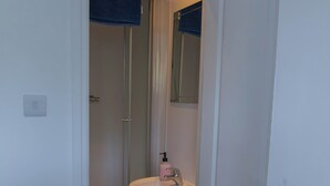 A bathroom with a white sink, a mirror, and a shower. - 5BR House | Free Parking | Fast Wi-Fi | Sleeps 10 (Wolverhampton)