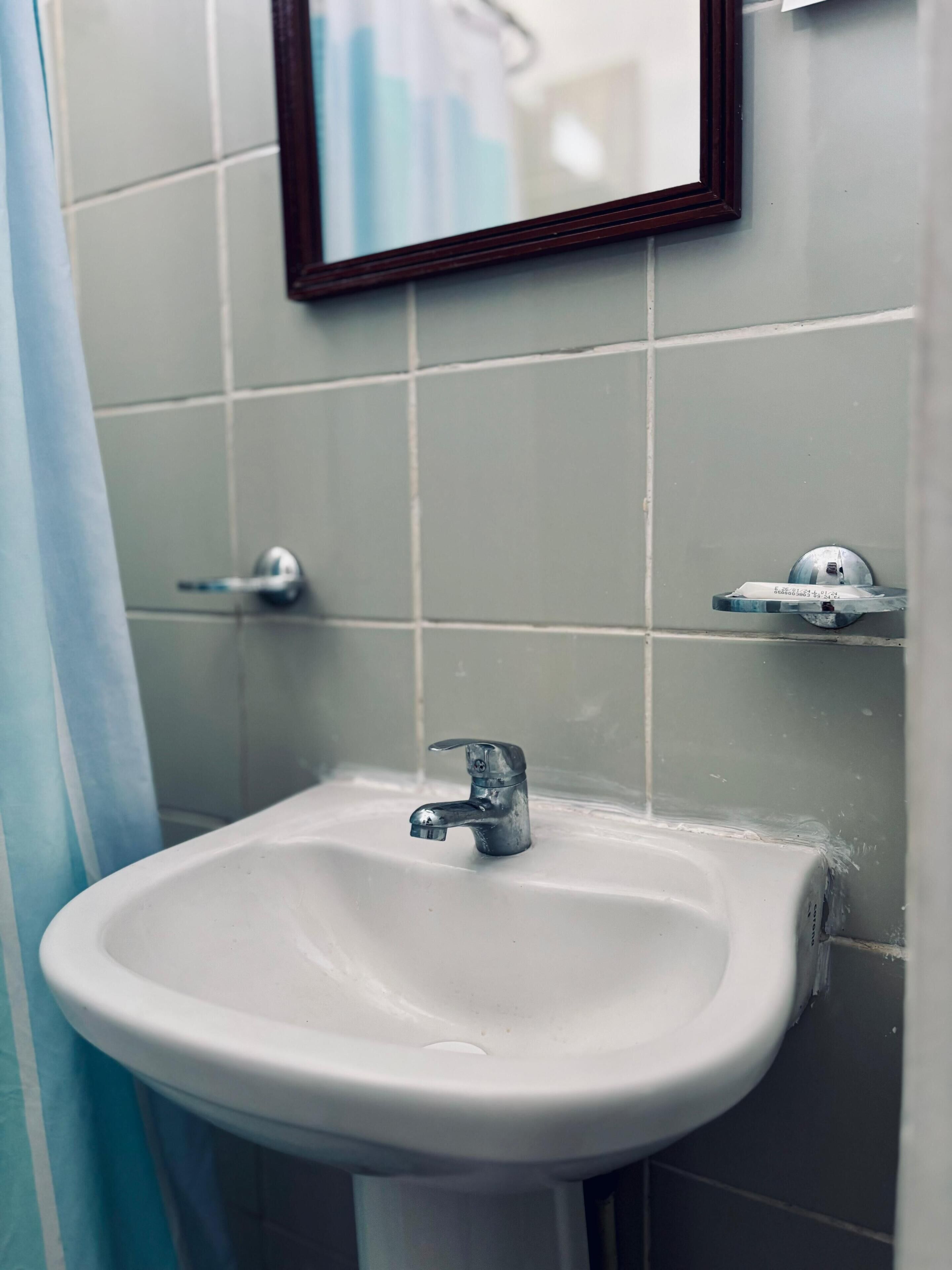 A bathroom with a white sink, a mirror, and a shower curtain.