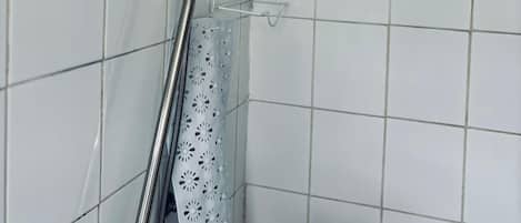 A shower area with a grab bar, a handheld showerhead, and a shower curtain.