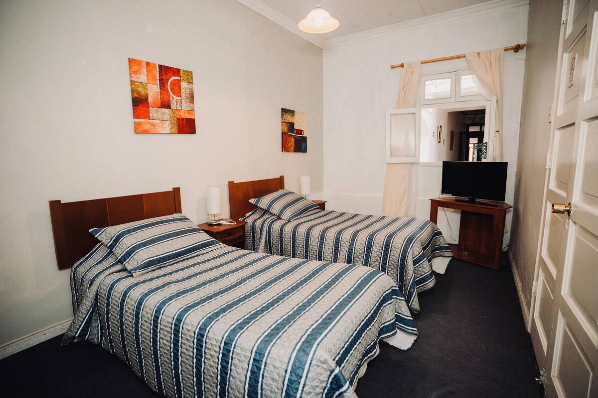 Una habitación de hotel con dos camas, televisión y obras de arte en las paredes.