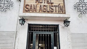 Un letrero de hotel que dice 'HOTEL SAN AGUSTIN' sobre una reja de metal negro.