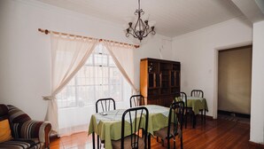 Un comedor con mesa y sillas de madera, un sofá y un armario.