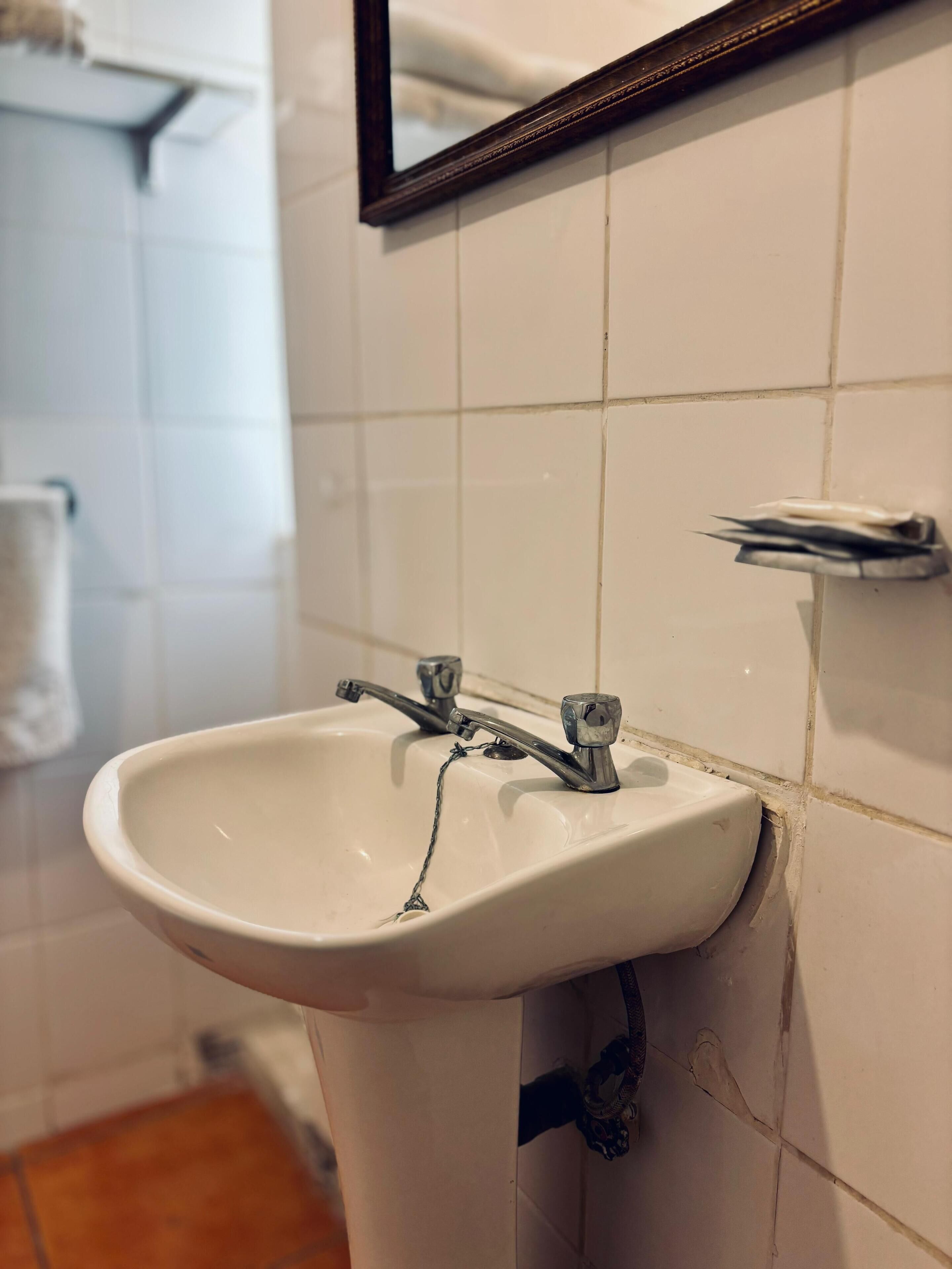 Une salle de bain avec un lavabo blanc, un miroir et un porte-serviettes.
