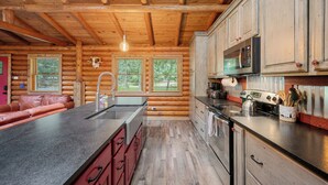 L’intérieur d’une cabane en rondins, avec une cuisine équipée d’armoires en bois, d’un évier et d’une cuisinière.