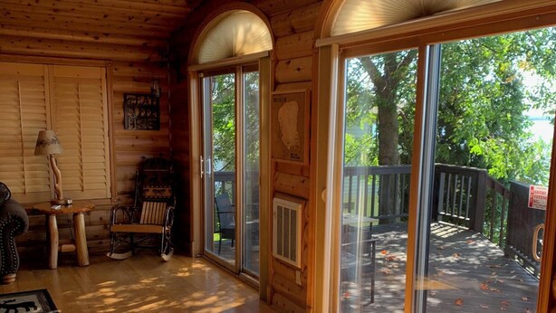 Interior de cabana de madeira com uma grande porta de correr de vidro que dá para um deck.