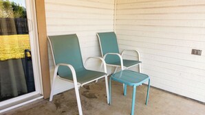 Un'area patio riparata con due sedie verdi e un tavolino.