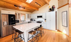 Una cucina moderna con una grande isola, elettrodomestici in acciaio inossidabile e pavimento in legno.