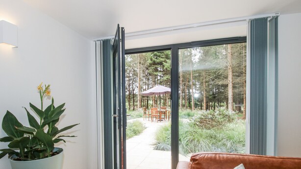 Una sala de estar moderna con un ventanal corredizo que da a un patio exterior.