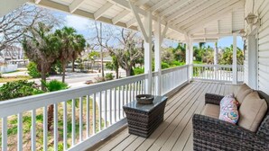 A covered porch with wicker furniture and a stone planter.
