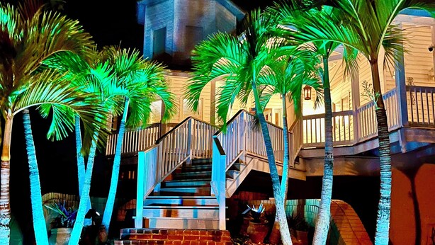 A staircase leading to a building with a private property sign, surrounded by palm trees and illuminated by artificial lighting.