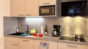 A kitchen with a microwave, coffee maker, and a sink.