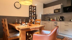 Uma sala de jantar com uma mesa de madeira, cadeiras e um relógio na parede.