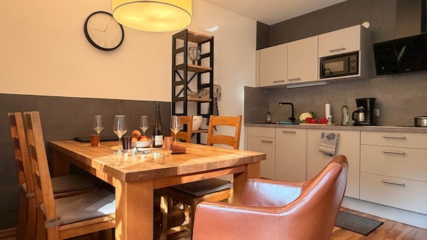 A dining area with a wooden table, chairs, and a clock on the wall.