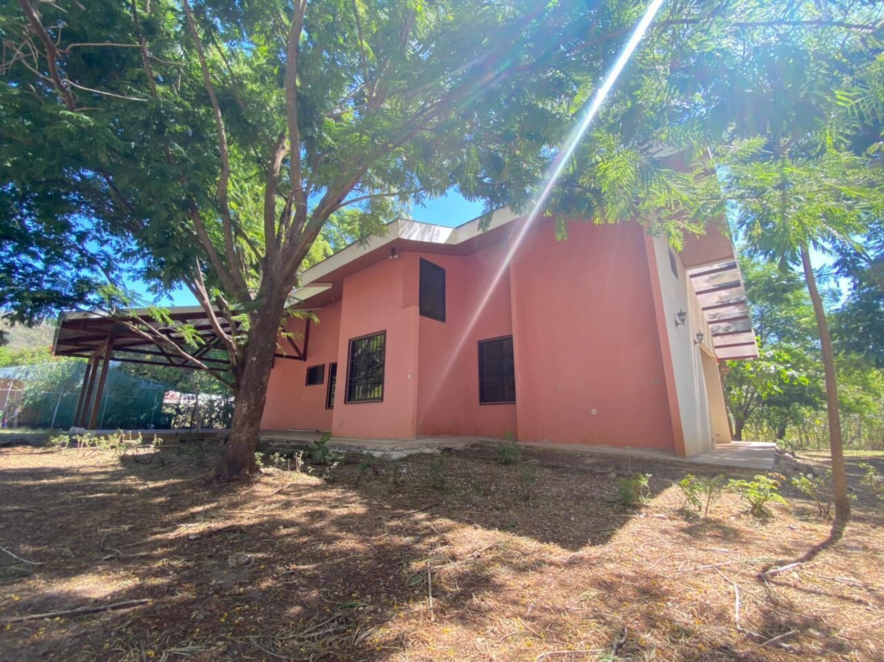 A single-story building with a pink facade, a small porch, and a covered outdoor seating area.