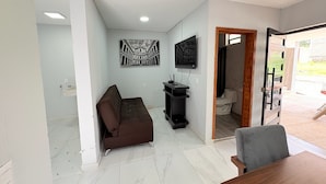 A living room with a brown sofa, a TV mounted on the wall, and a small black cabinet. - Residencia Gran Coyula Orange 512 (Tonalá)
