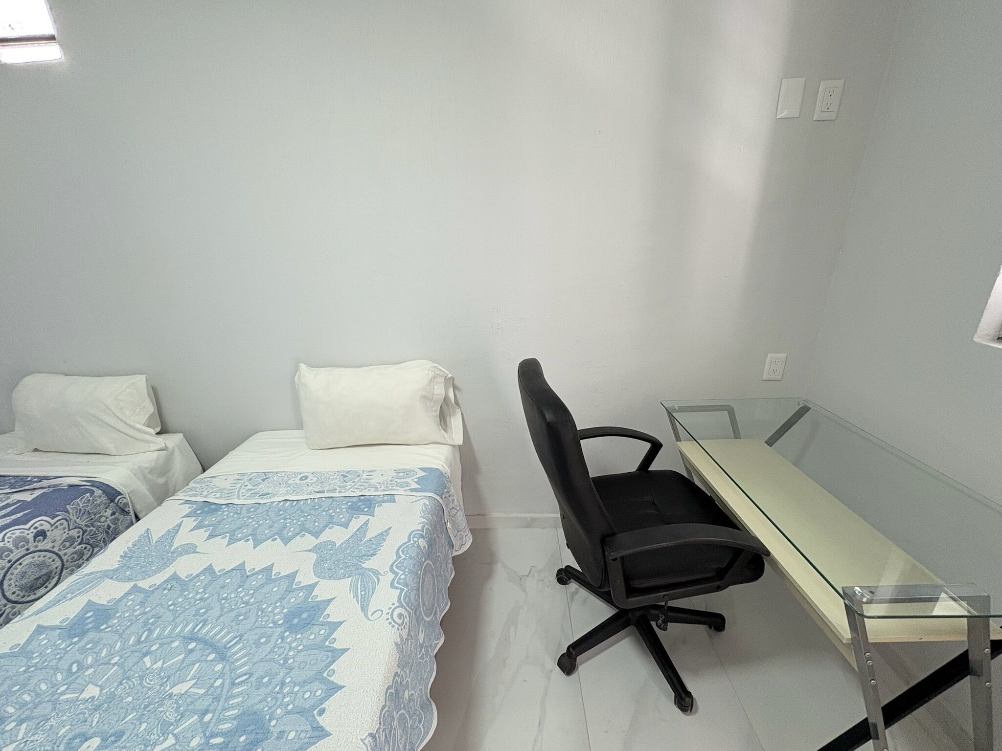 Ein Zimmer mit zwei Betten, einem Schreibtisch und einem Stuhl.
