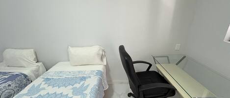 Ein Zimmer mit zwei Betten, einem Schreibtisch und einem Stuhl.
