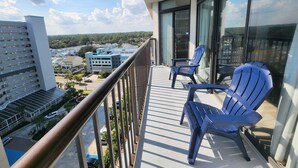 A balcony with two chairs, a view of a parking lot, and buildings in the background. - Our Newest Premium Ocean View Property - 2BR/2BA: Sleeps 8 - Top Amenities! (Myrtle Beach)