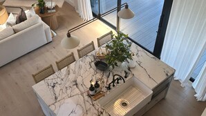 A modern kitchen with a marble countertop, a sink, and a dining area with chairs and a plant. - Don Pedro Island: Canal w. dock and 5-Min to Beach (Englewood)