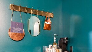 Ein Badezimmer mit Holzschrank, Waschbecken, Spiegel, Handtuchhalter und einer Kaffeemaschine.