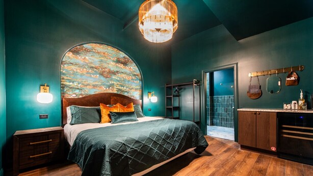 Ein modernes Schlafzimmer mit einem großen Bett, Holzboden, einer einzigartigen Wandmalerei und einem eingebauten Kleiderschrank.