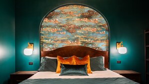 Ein Schlafzimmer mit einem großen Bett, zwei Nachttischen, einem Holz-Kopfteil und Wandleuchten.