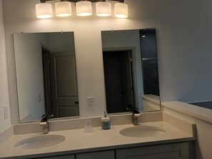 Une salle de bain avec deux lavabos, un miroir et un luminaire au-dessus.