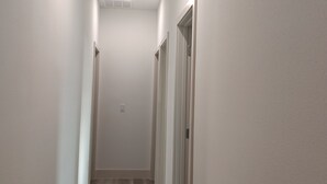 A narrow hallway with white walls and a wooden floor, leading to a door at the end. - beautiful vacation home (Ocala)
