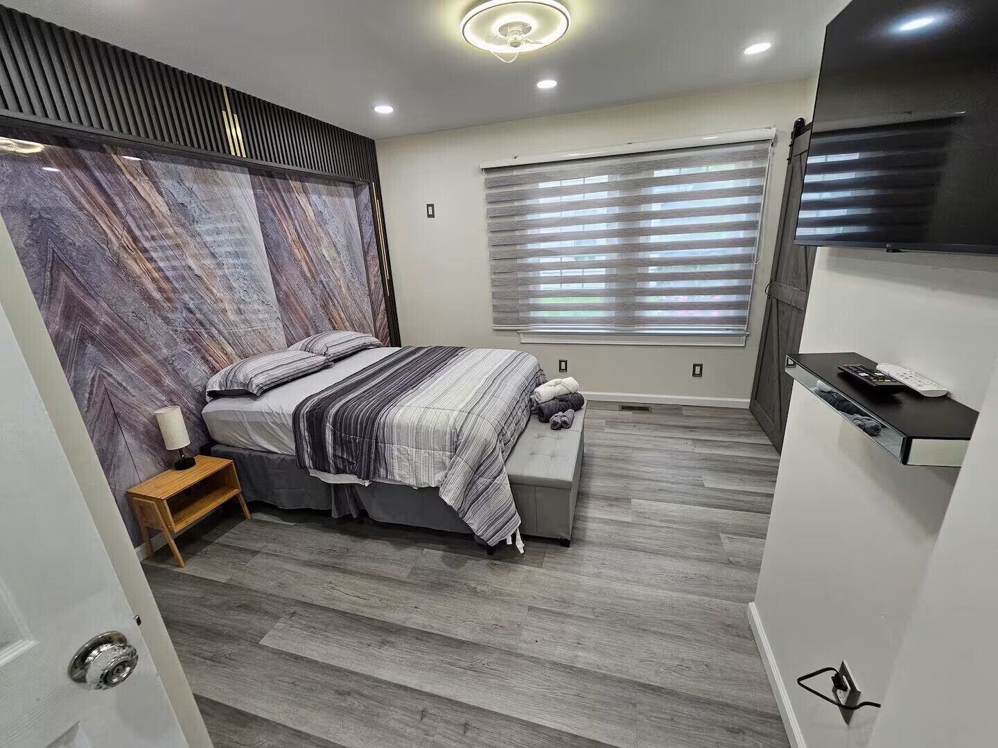 A modern bedroom with a bed, bedside table, and a built-in TV shelf.